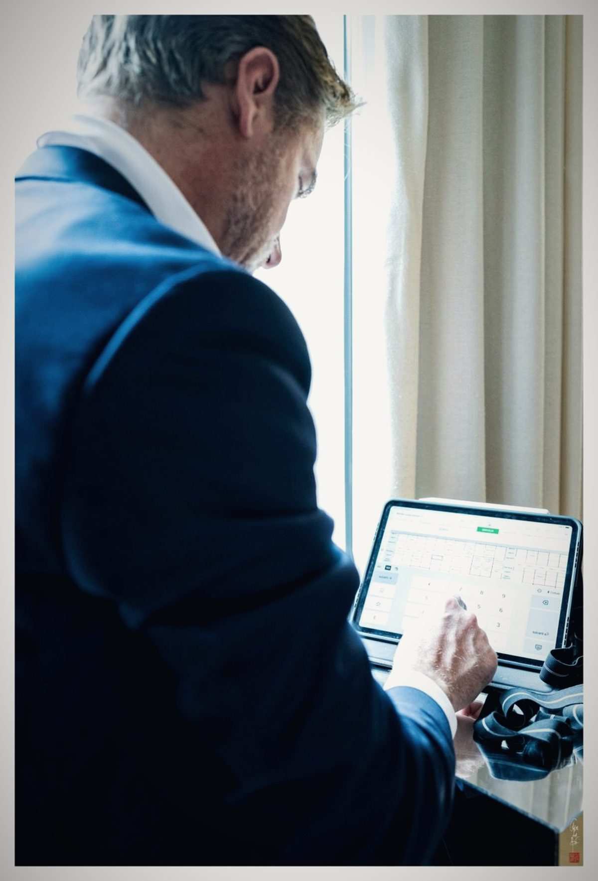 Le conseiller saisit les mesures d'un client sur une tablette, près d'une fenêtre