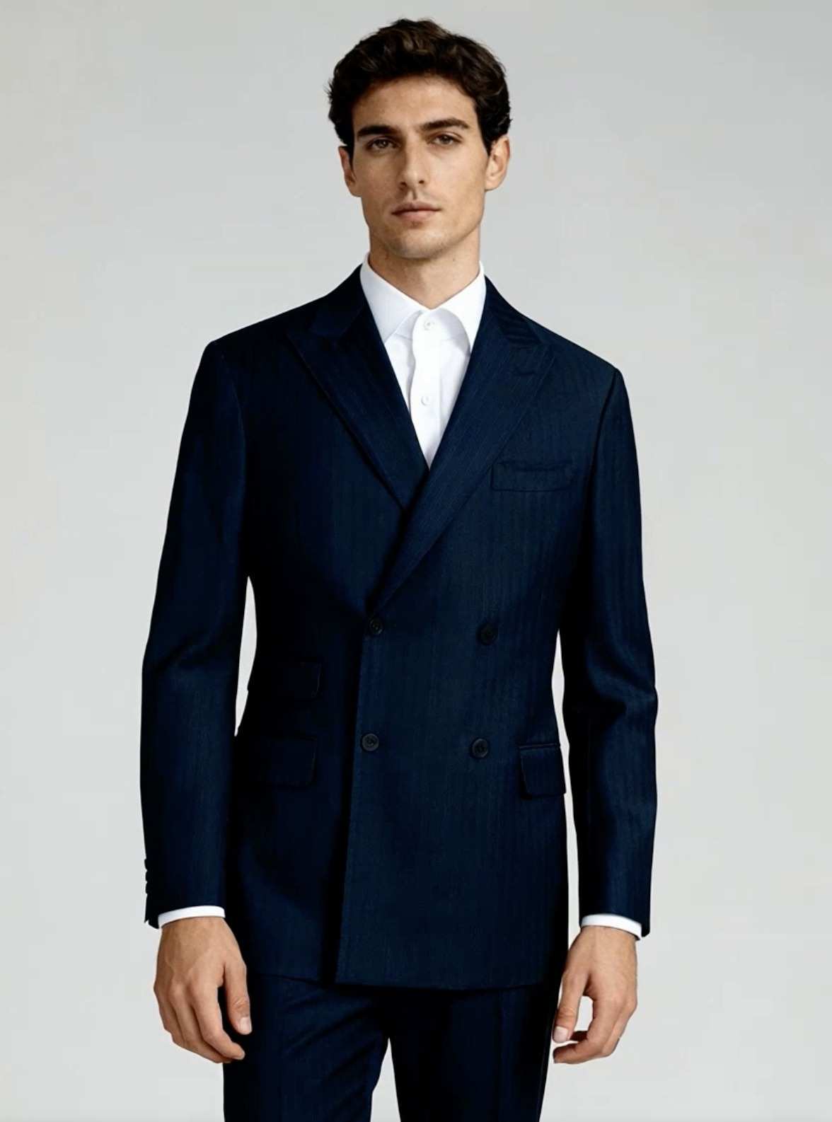 Costume croisé bleu marine porté avec une chemise blanche ouverte