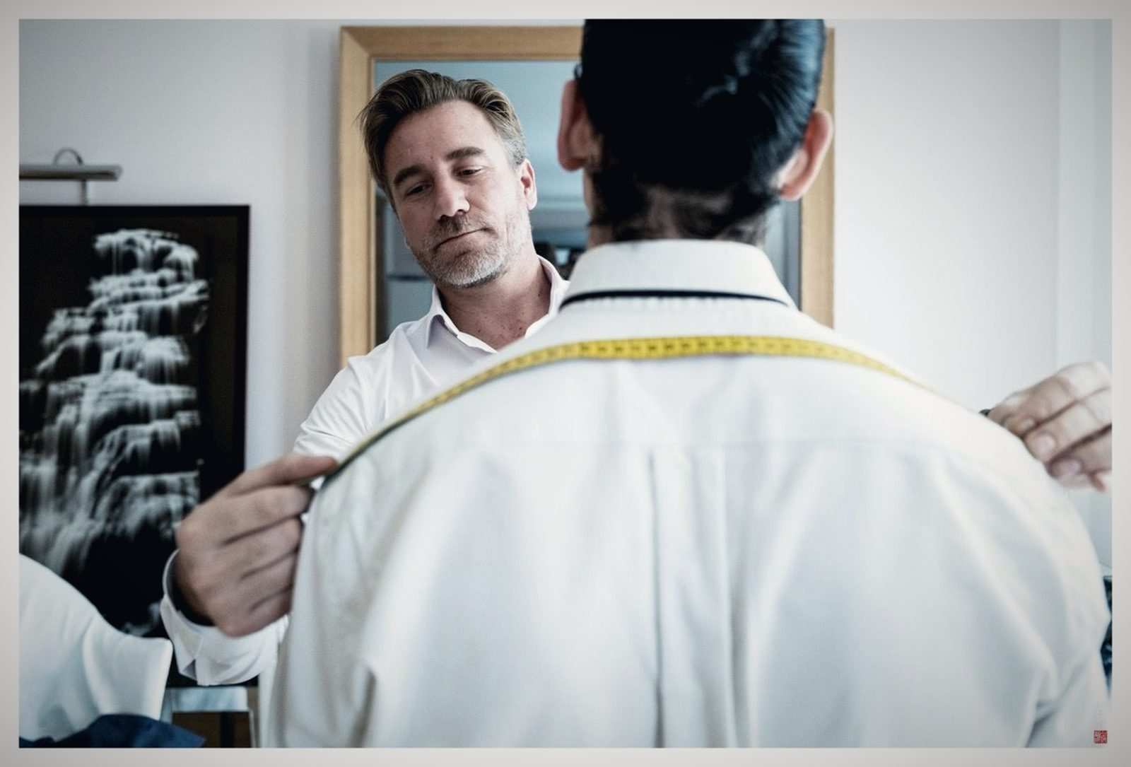 Prise de la carrure au mètre ruban sur la chemise blanche d'un client, de dos