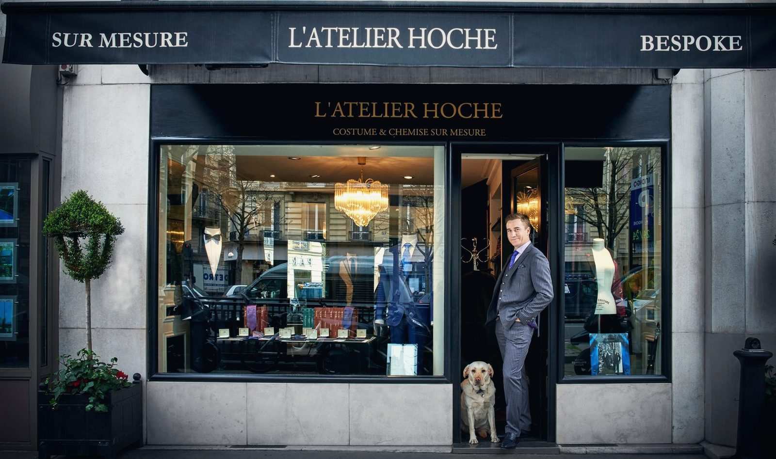 Façade de la boutique L'Atelier Hoche, le fondateur et son labrador sur le seuil