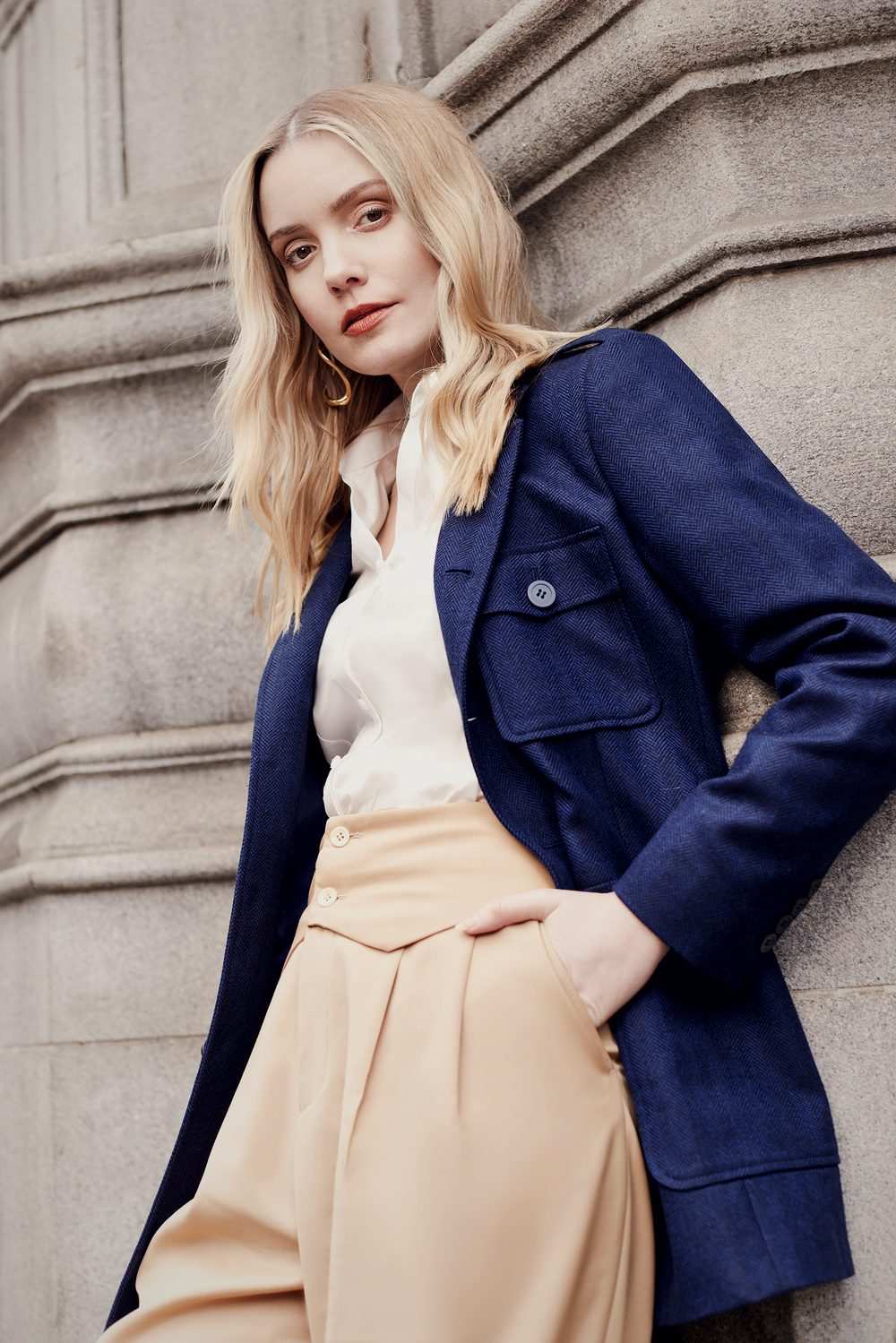 Femme en veste bleu marine à chevrons et poches plaquées, pantalon beige taille haute