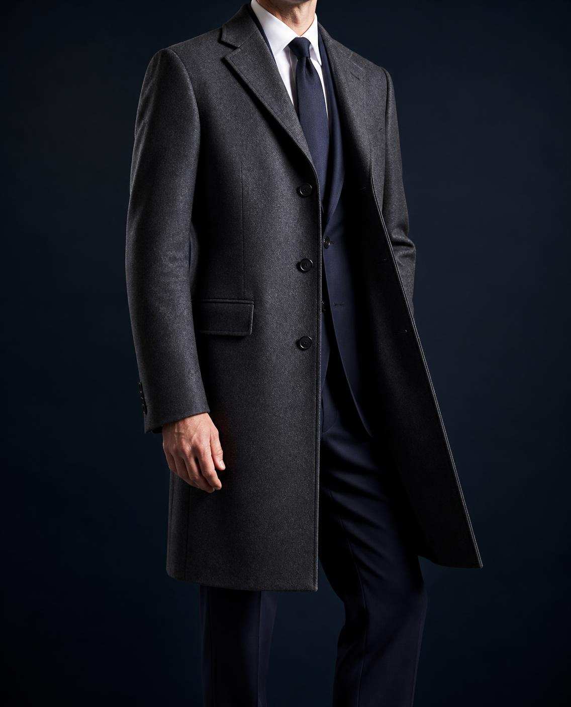 Manteau droit gris anthracite au genou, col cranté, porté sur un costume marine