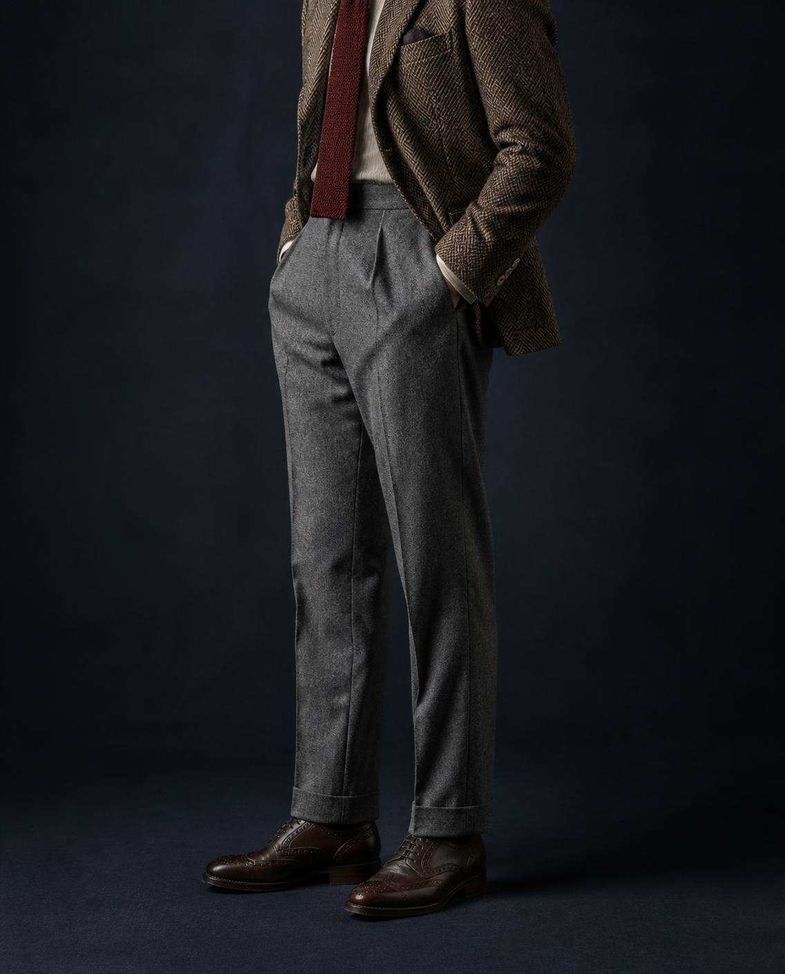 Pantalon de flanelle grise à revers, sous une veste de tweed