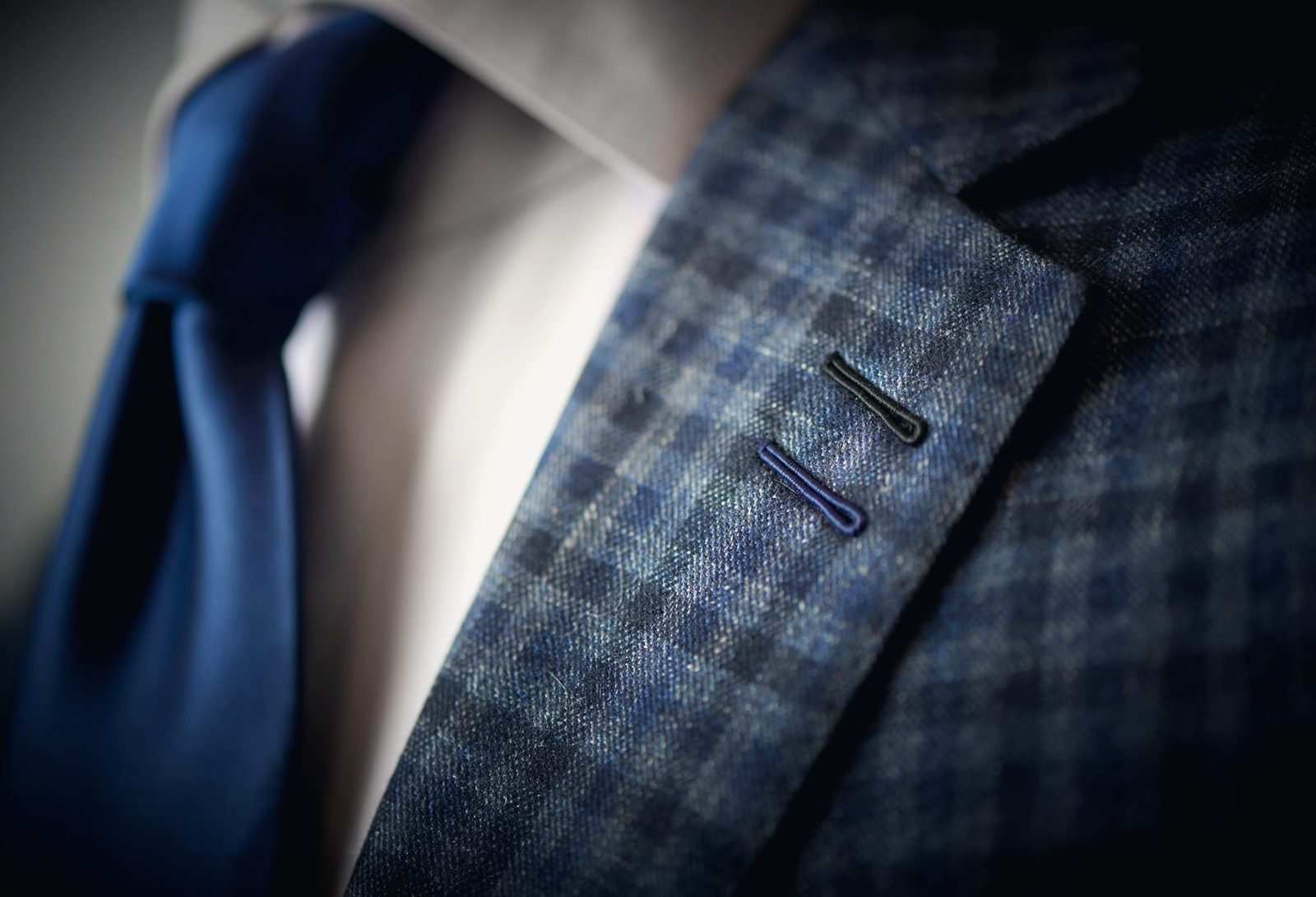 Revers d'une veste à carreaux bleus avec deux boutonnières, cravate bleu roi
