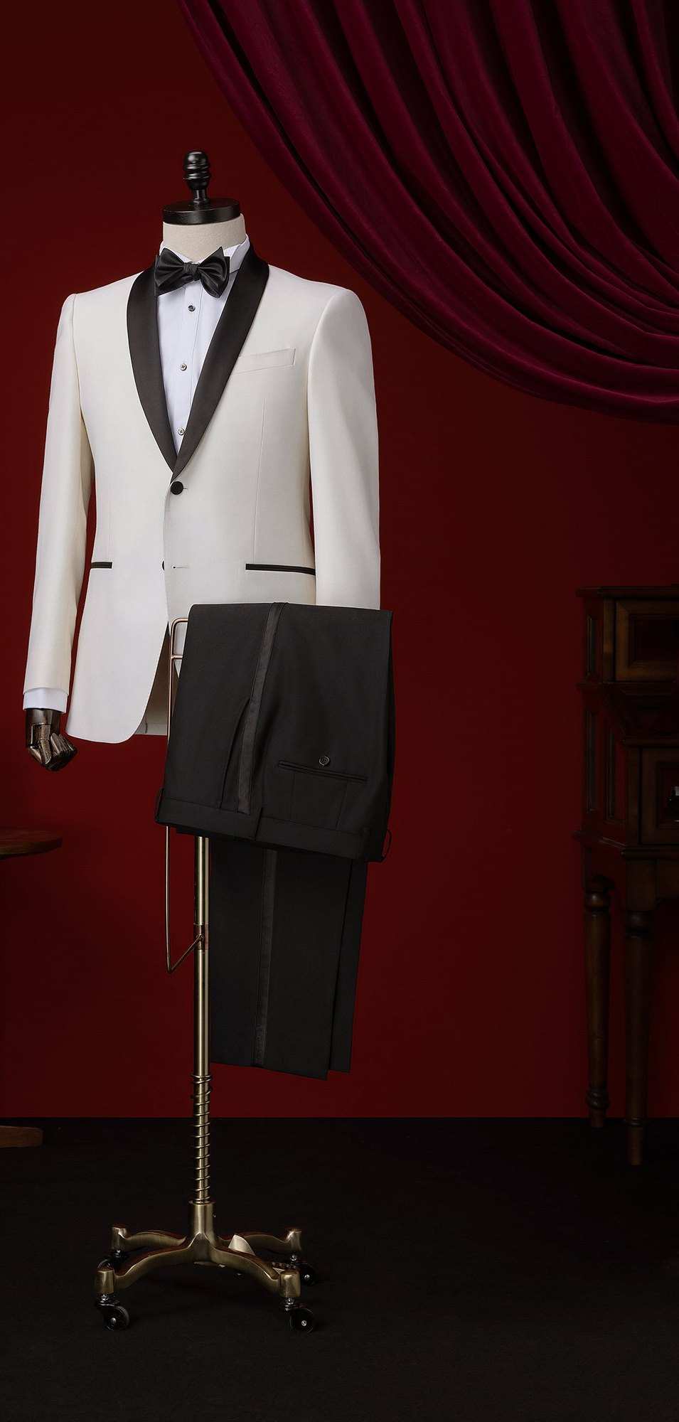 Smoking ivoire à col châle noir et poches passepoilées de noir, pantalon noir à galon, sur un buste