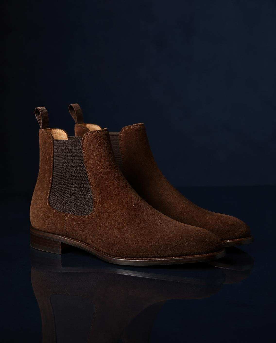 Paire de bottines chelsea en daim tabac, sur fond bleu nuit