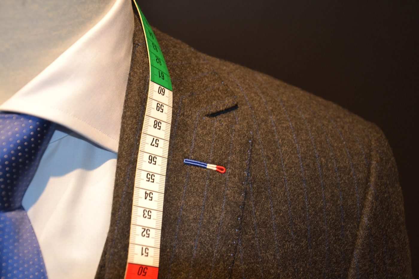 Boutonnière milanaise tricolore sur une flanelle rayée, mètre ruban sur l'épaule